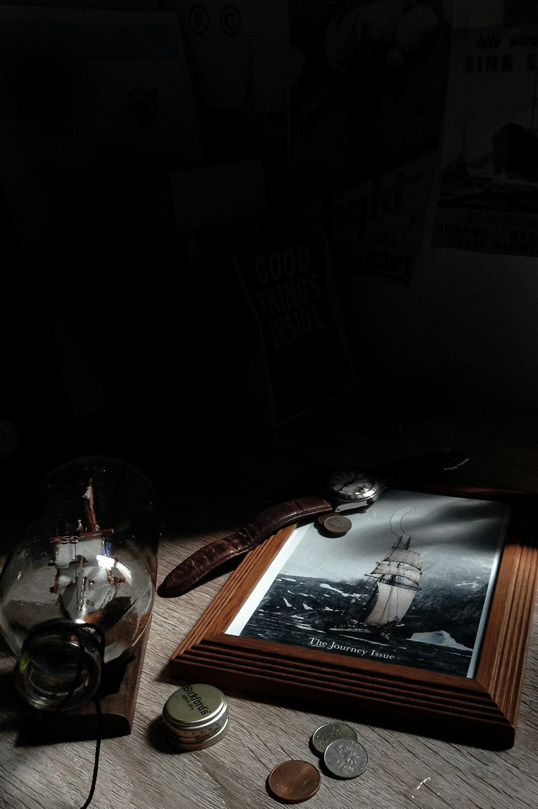 Detective notebook with magnifying glass and old photographs on a dark wooden desk lit by a desk lamp